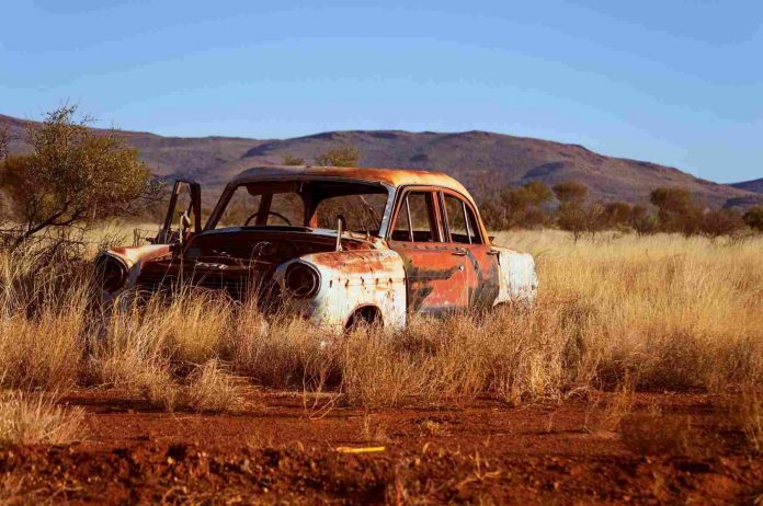 A rusty old car resting in a desert.