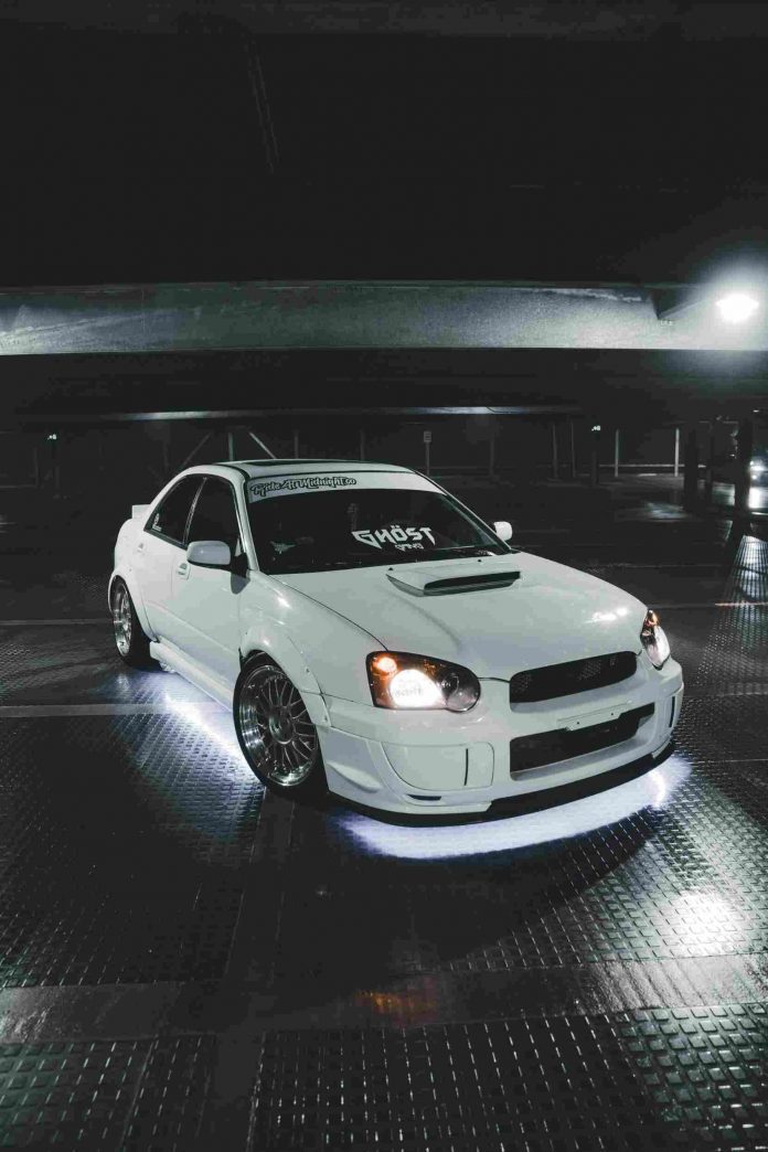 A white sportscar inside a dark garage.